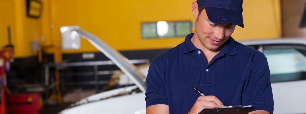 Male car mechanic looking at clipboard