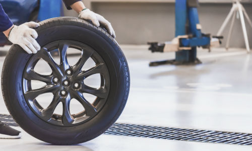 Mechanic rolling car tire on floor