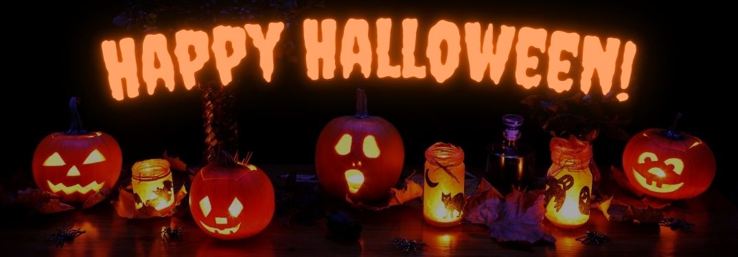 Lit Halloween Jack-o-Lanterns and Candles on a Table with Glowing Orange Happy Halloween Text