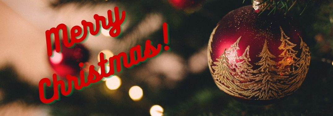 Close Up of a Christmas Ornament on a Tree with Red Merry Christmas Text