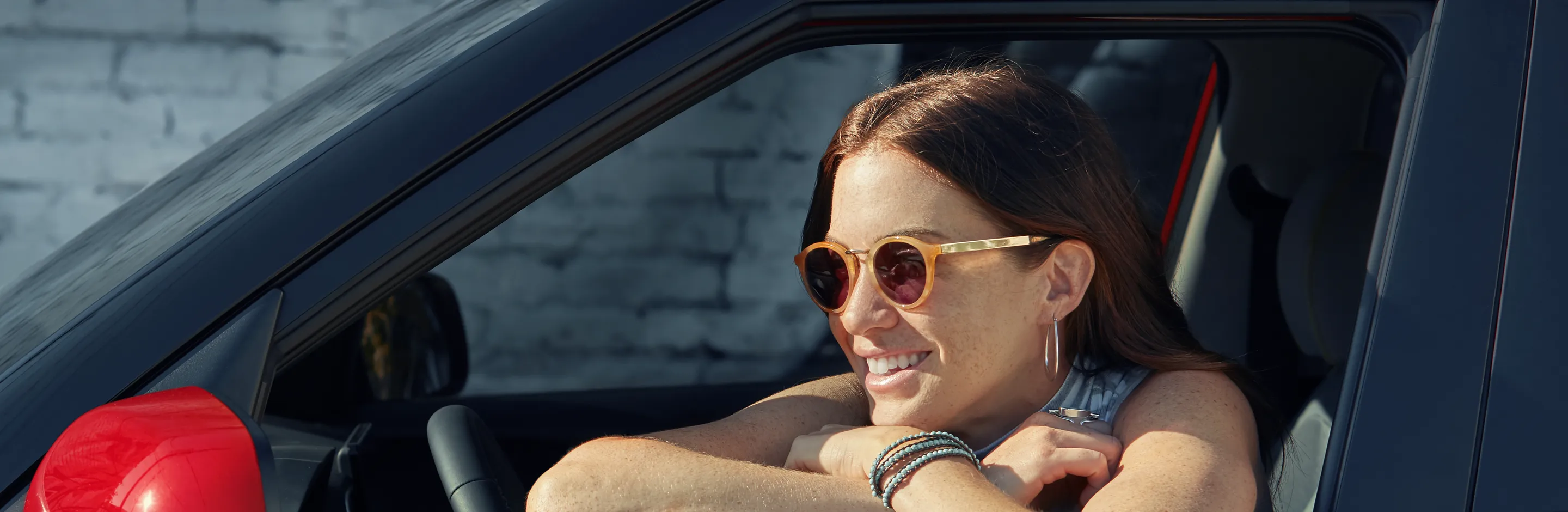 Smiling woman in sunglasses leaning out of a new Hyundai window