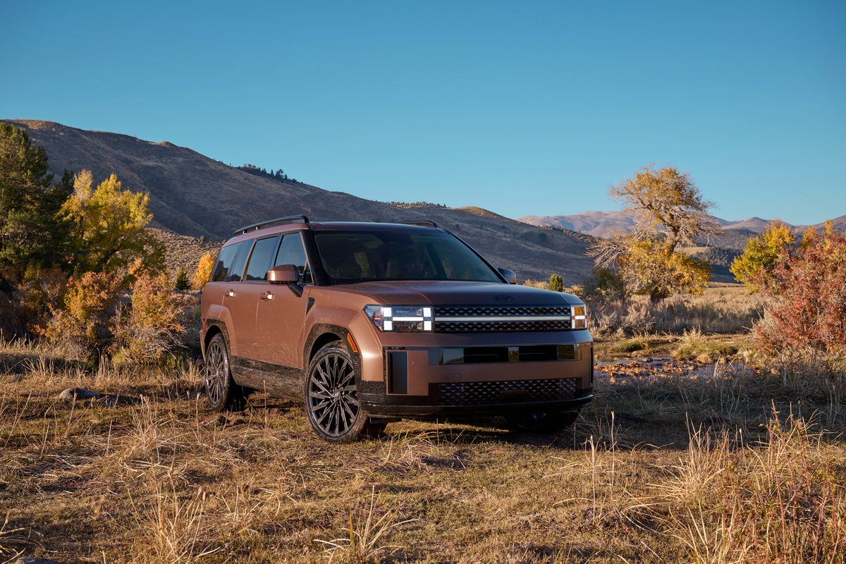 A brown 2026 Hyundai Santa Fe Hybrid in Phoenix is parked facing the viewer to the right by a dry creek bed in a desert valley.